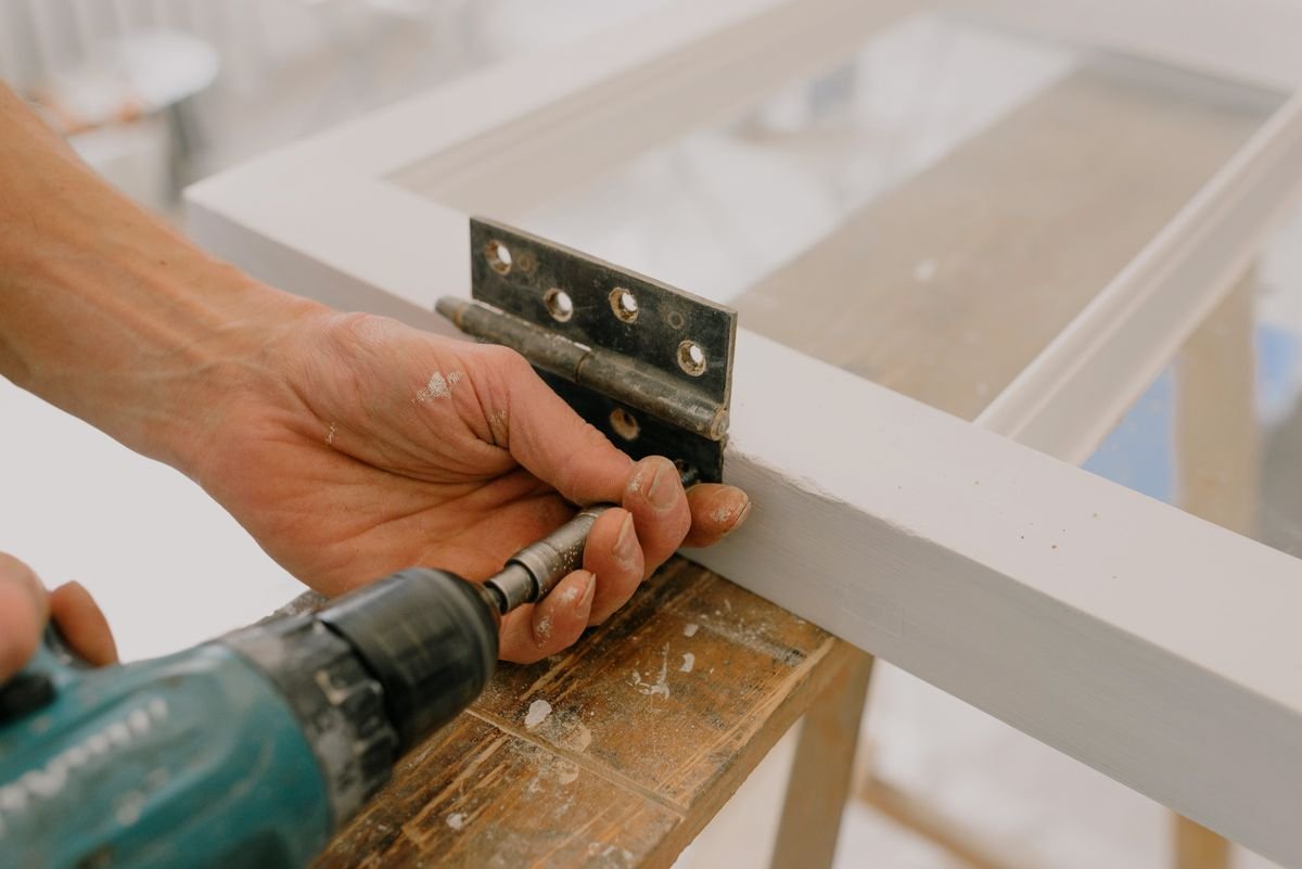 Carpenter fitting a hinge to a new door